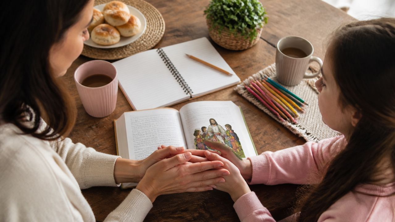 Mesa com Bíblia, caderno e mãos de mãe e filha em um momento simples de oração em casa
