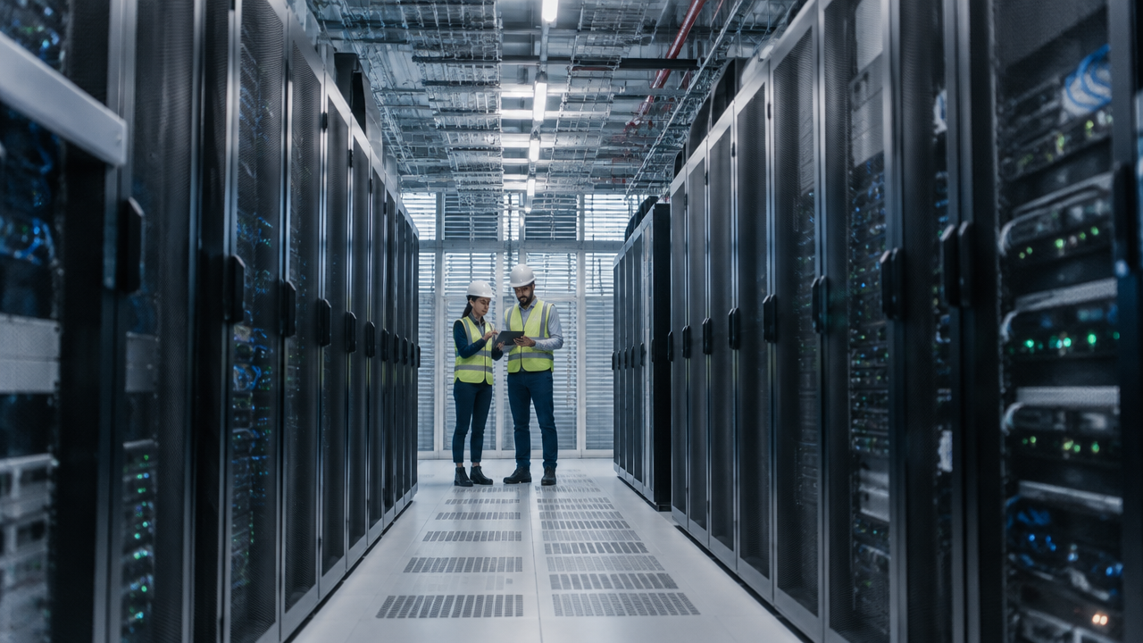 Profissionais de engenharia analisam um projeto em corredor moderno de data center com racks de servidores