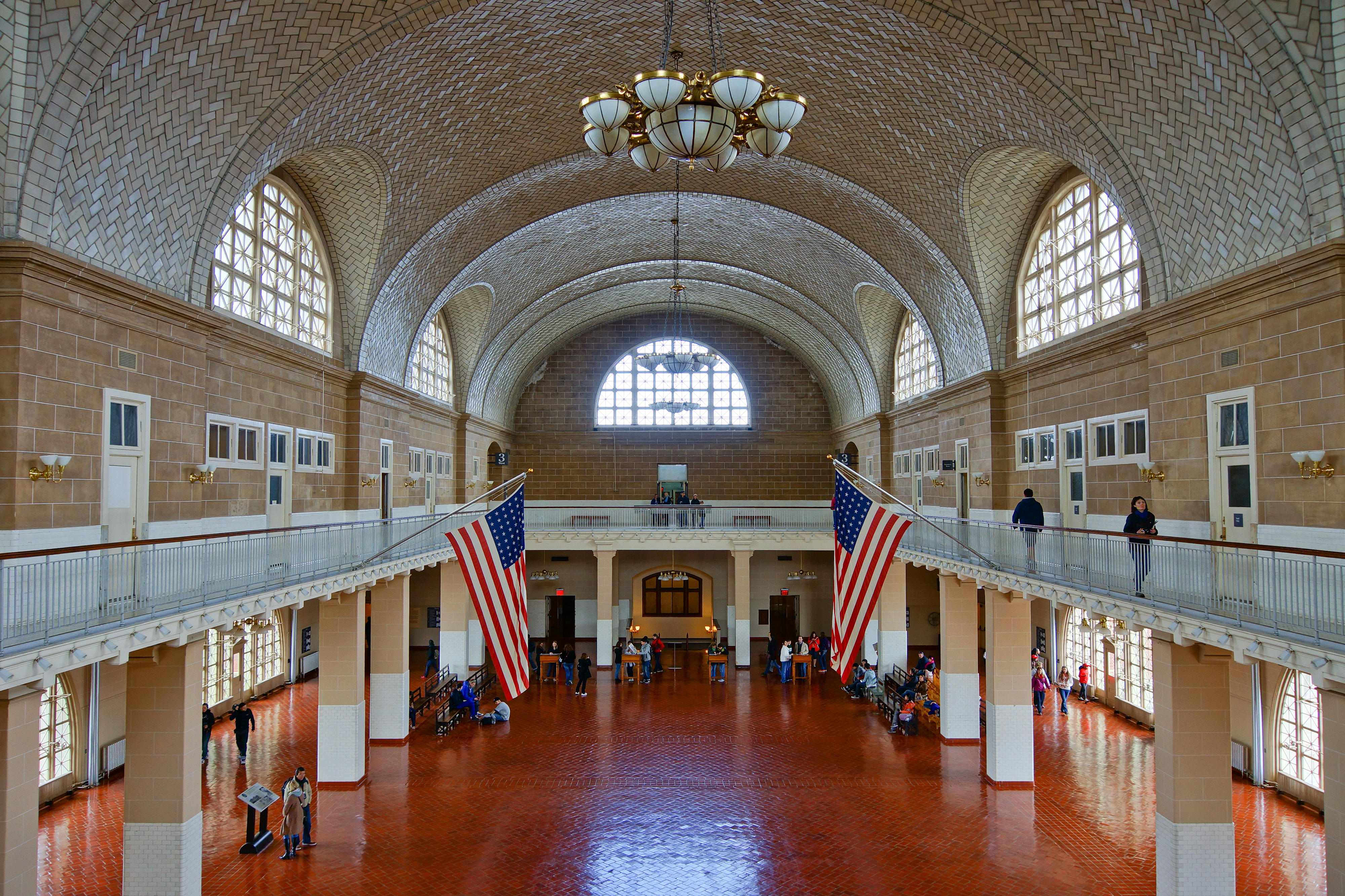 Historic immigration hall at Ellis Island with travelers waiting for inspection