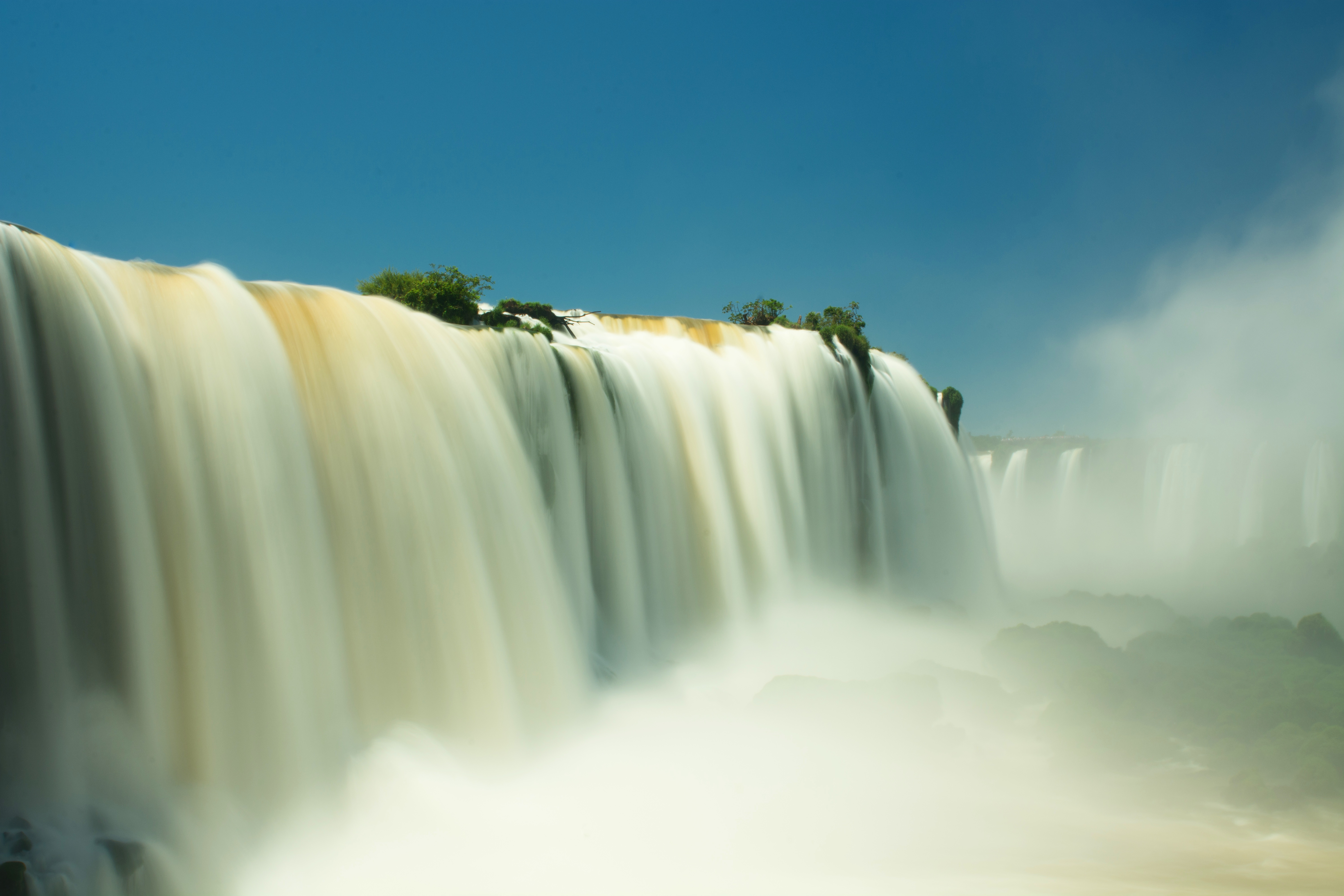 Vista ampla das Cataratas do Iguaçu com passarelas e grande volume de água