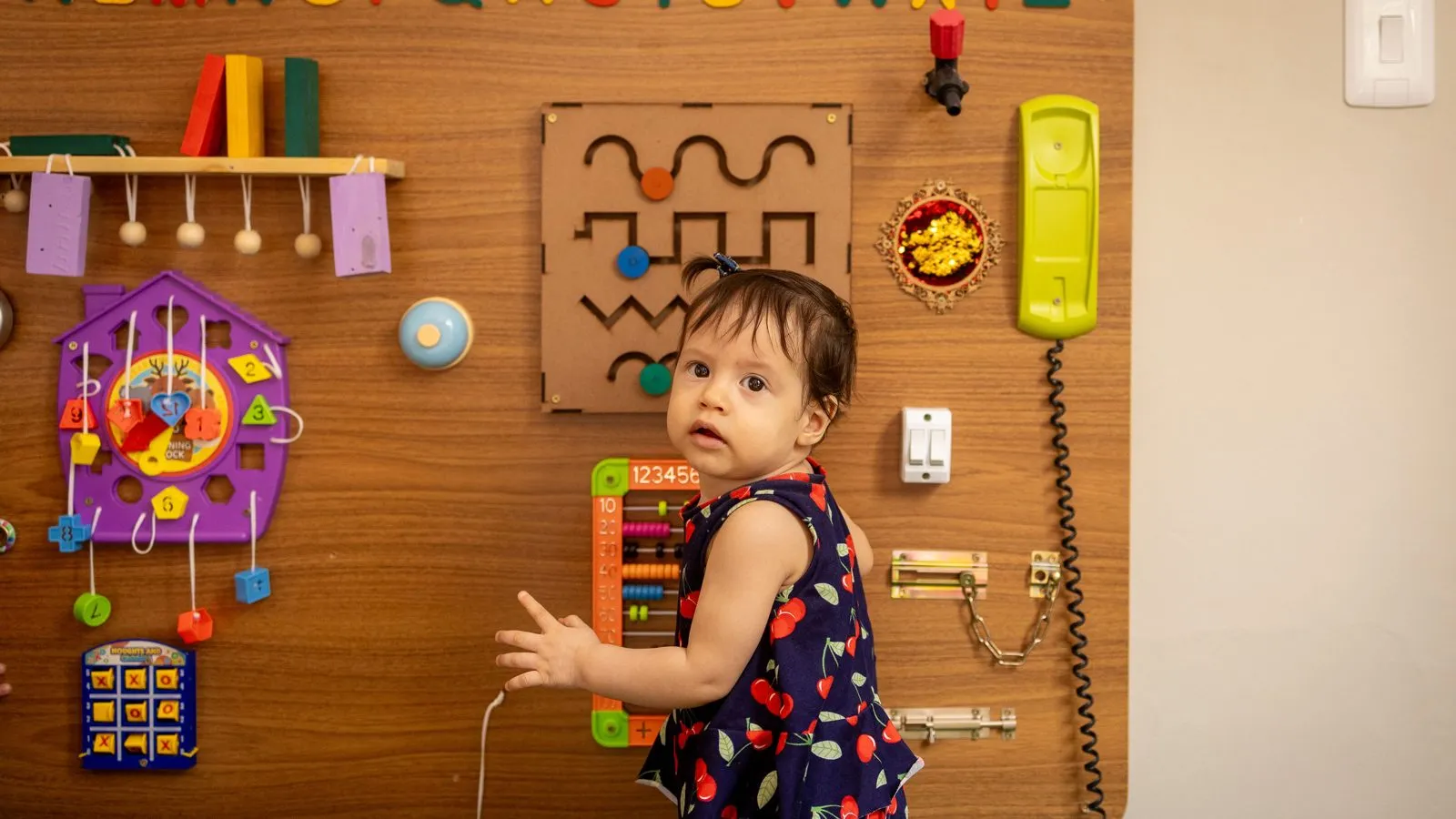Criança explora um painel sensorial com peças de encaixar, girar e apertar na Baby Gym Manaus.