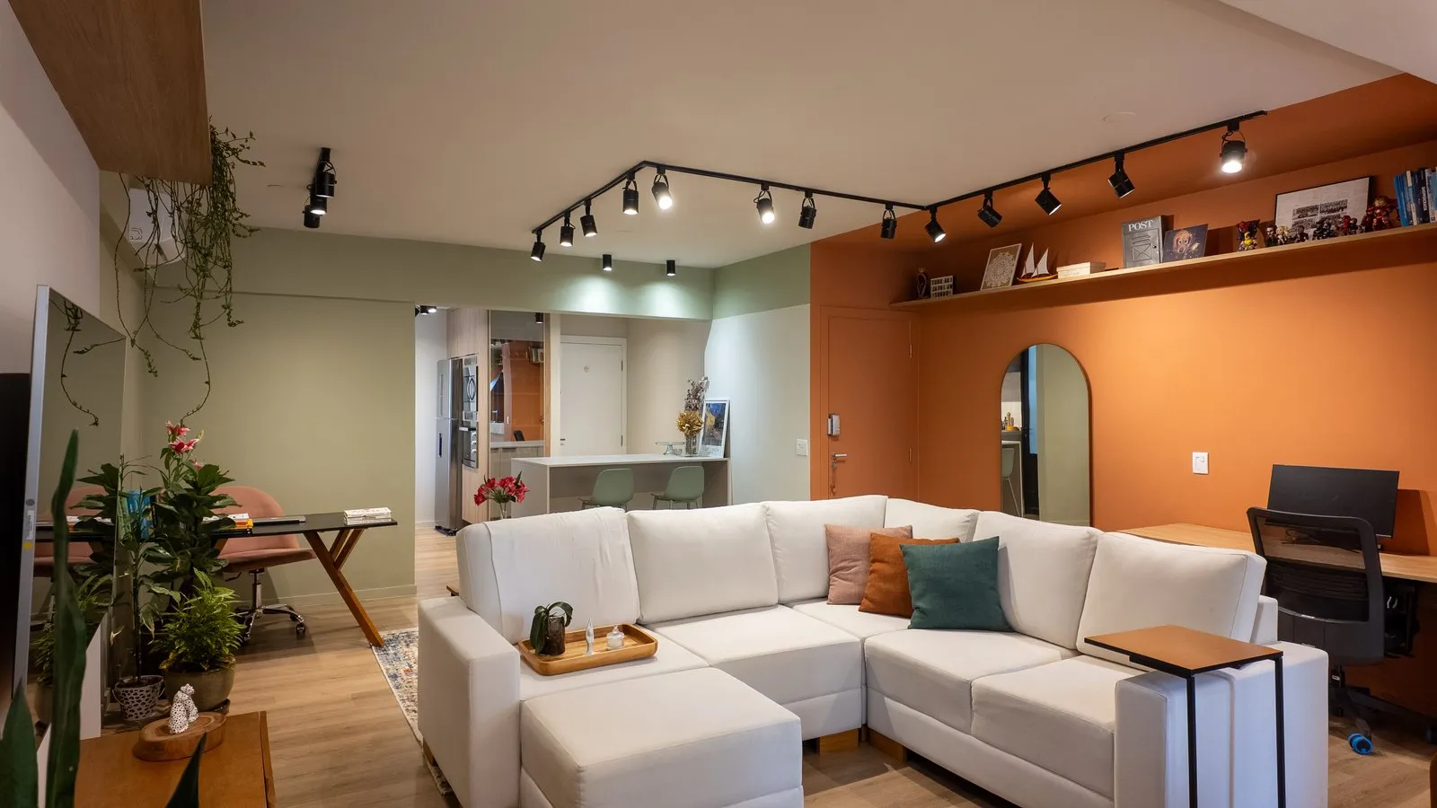 Sala integrada reformada pela Decorafit com sofá em L e parede laranja