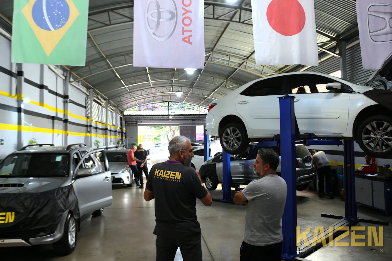 Interior de oficina automotiva organizada com técnicos realizando diagnóstico em carros em Belo Horizonte